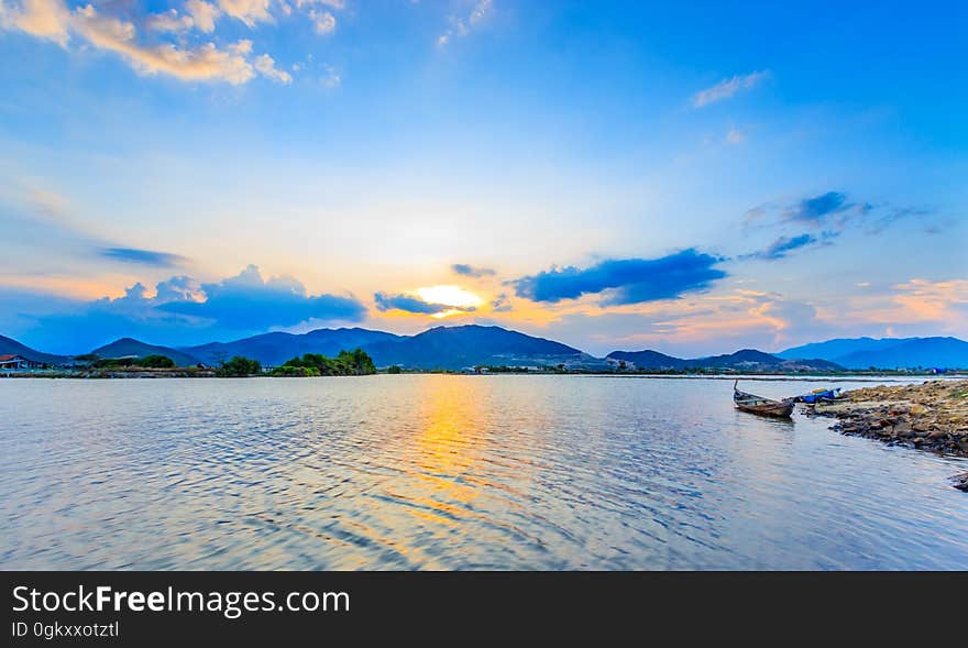 Sunset over island coastline with boat in foreground.