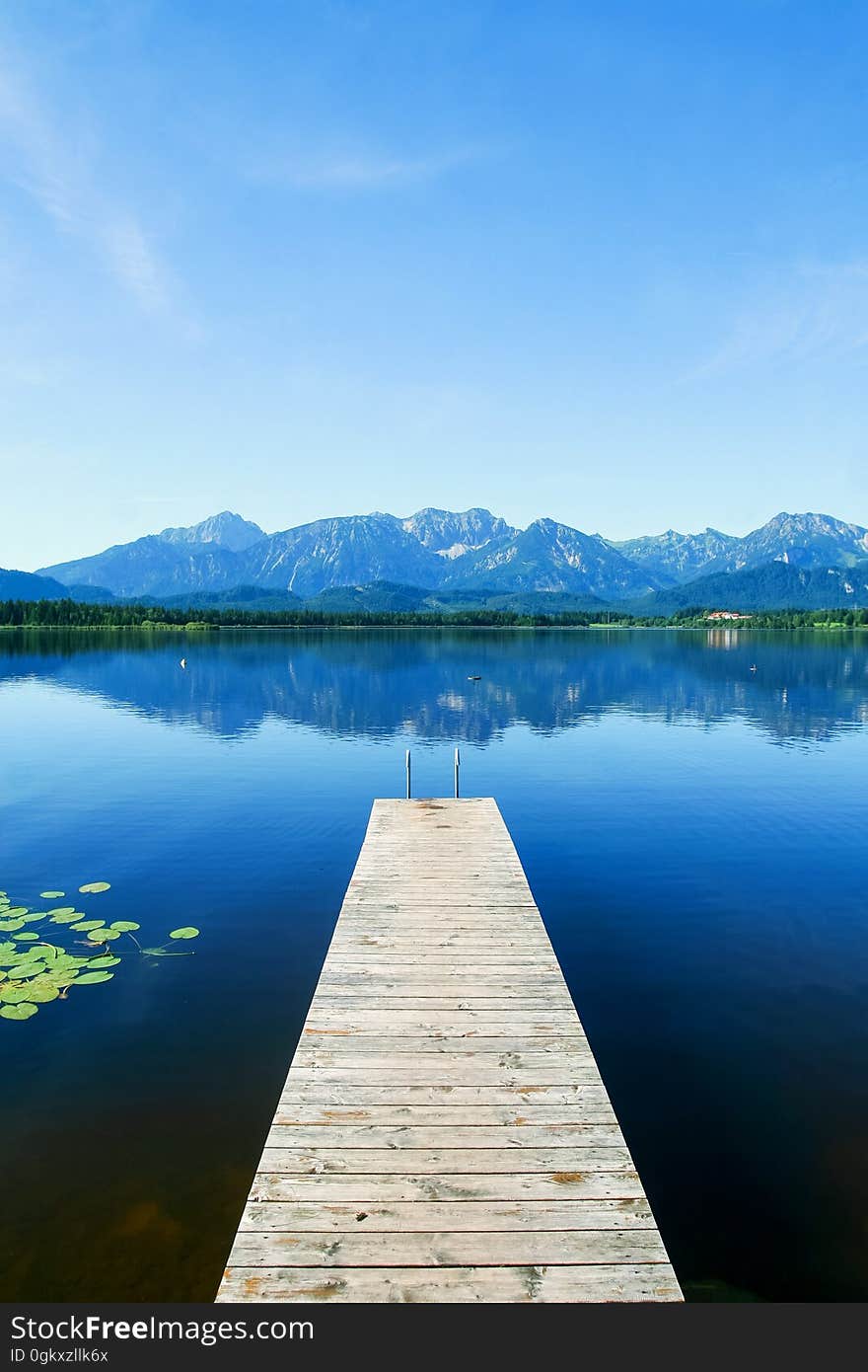 A wooden pier on a lake and mountains in the background. A wooden pier on a lake and mountains in the background.