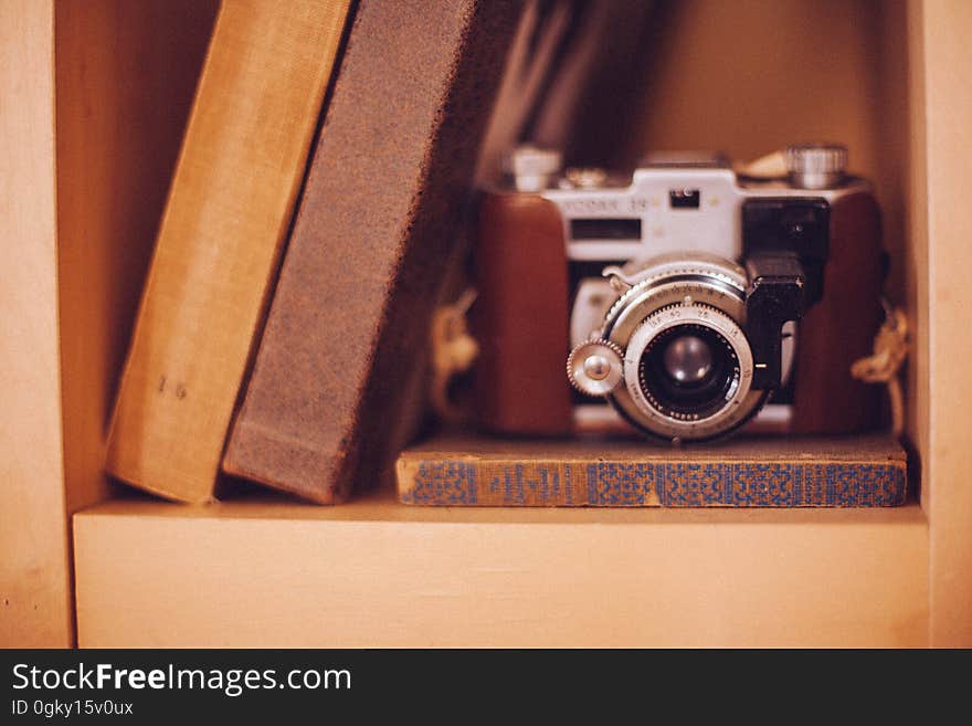 An old analog film camera in a bookshelf with books. An old analog film camera in a bookshelf with books.