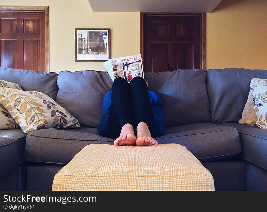 A person sitting on a sofa reading a book. A person sitting on a sofa reading a book.