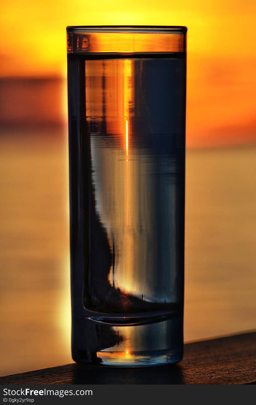 A glass of water illuminated by a sunset.