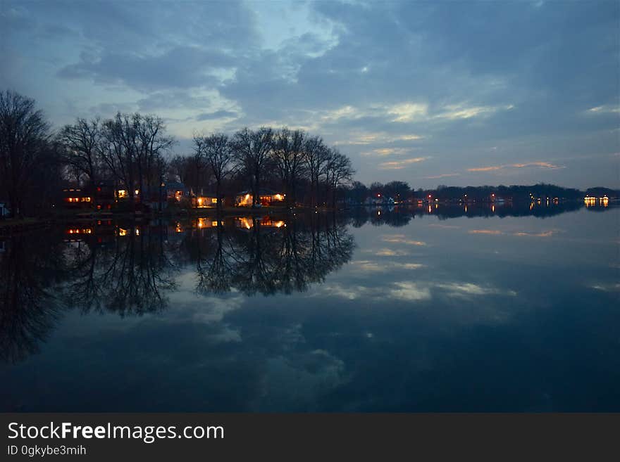 Houses with lights by the shore of a lake at night. Houses with lights by the shore of a lake at night.