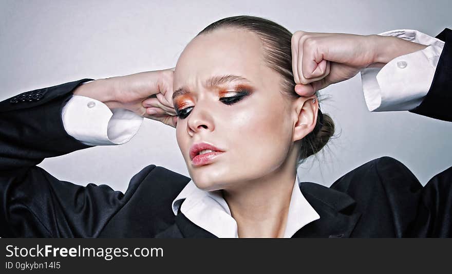 A woman holding hands in fists on her temples. A woman holding hands in fists on her temples.