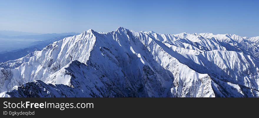 Cold mountain landscape with sunlit areas and areas in shadow, a challenge to both climbers and dedicated mountaineers, pale blue sky. Cold mountain landscape with sunlit areas and areas in shadow, a challenge to both climbers and dedicated mountaineers, pale blue sky.