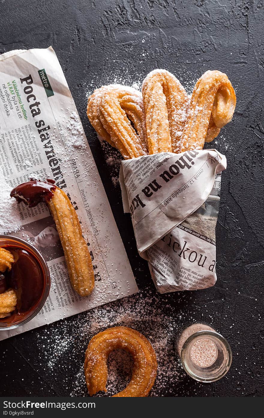 Freshly baked churros wrapped in newspaper.