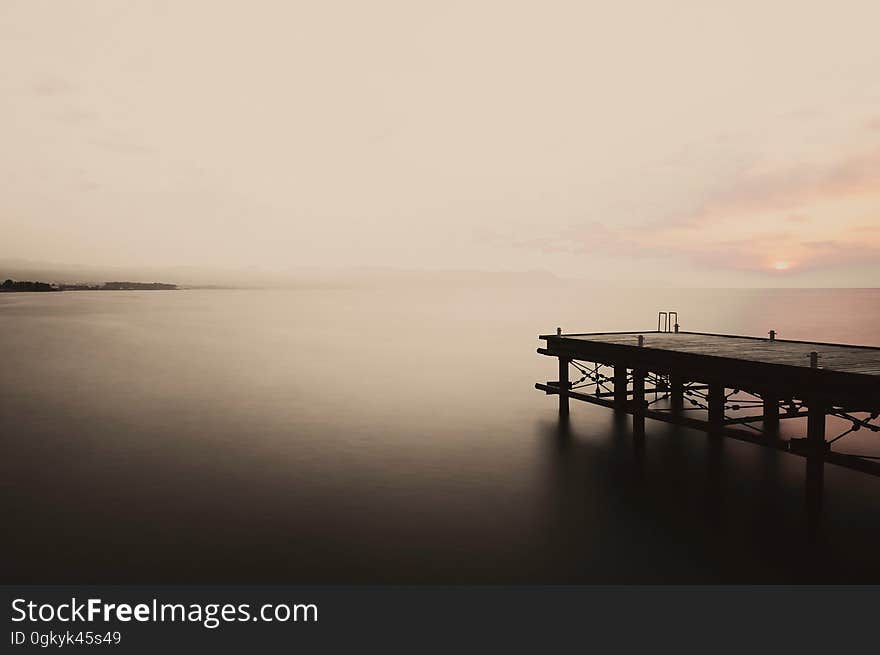 A seascape with a jetty at sunset.