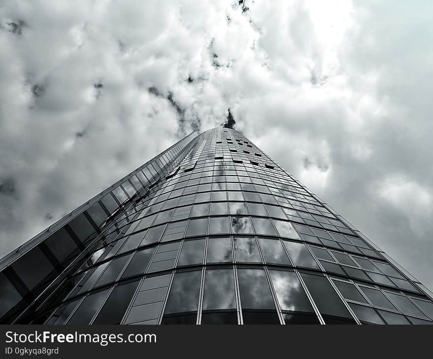 A glass skyscraper against the cloudy skies.