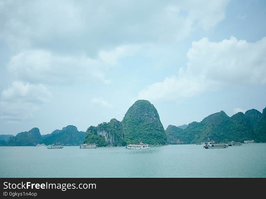 A view of a sea with karsts and ships in front of them. A view of a sea with karsts and ships in front of them.