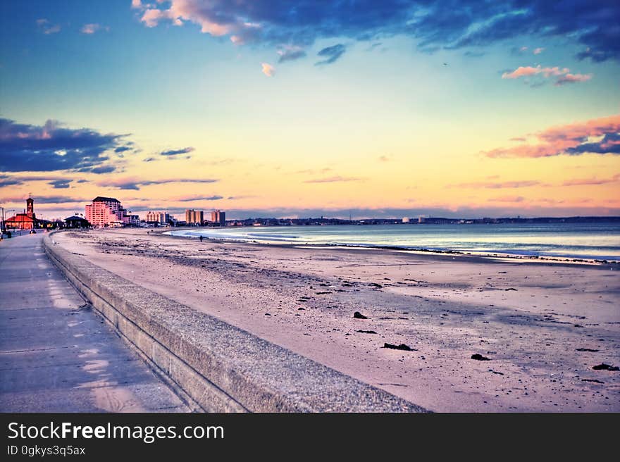 Resort beach at sunset looking along boardwalk with cloudscape background.