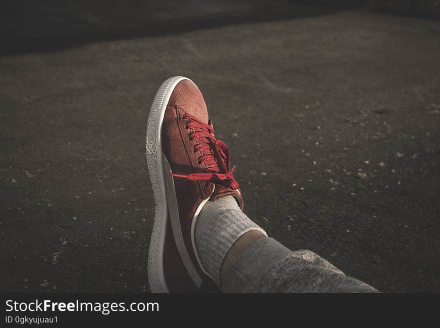 A close up of a foot in a sneaker resting on the ground. A close up of a foot in a sneaker resting on the ground.