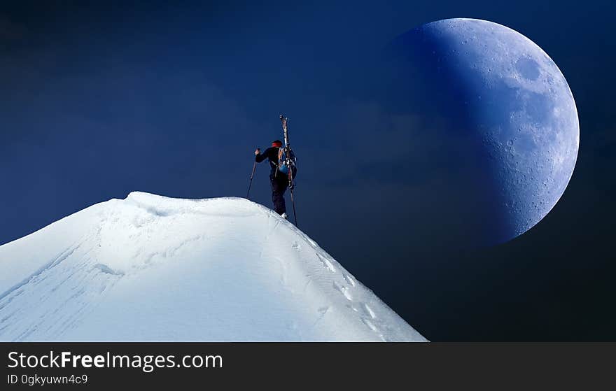 A mountain climber reaches the top of a mountain summit. A mountain climber reaches the top of a mountain summit