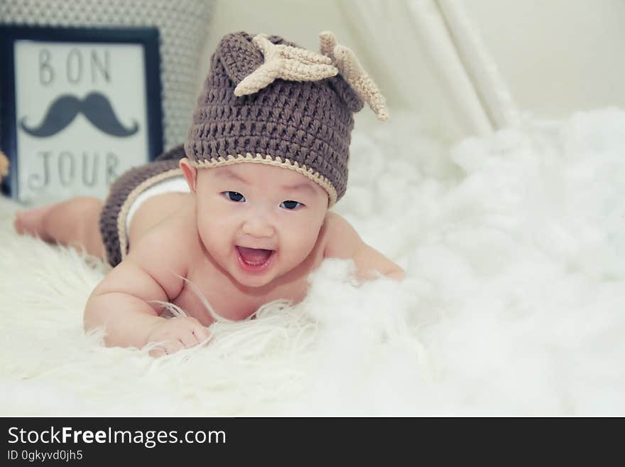 A smiling baby boy with a woolen cap on a bed. A smiling baby boy with a woolen cap on a bed.