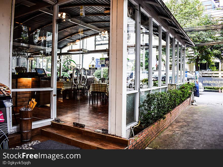 Tables and chairs inside glass enclosed restaurant dining room from outside on sunny day. Tables and chairs inside glass enclosed restaurant dining room from outside on sunny day.