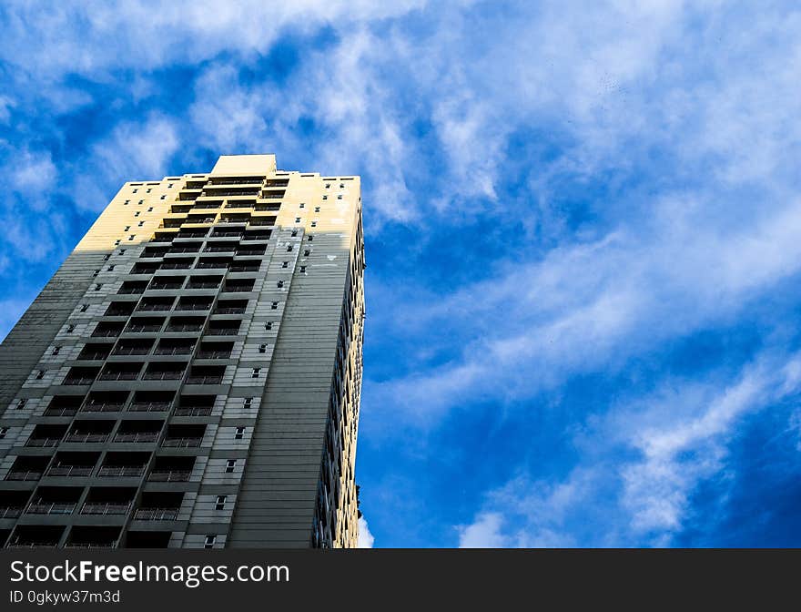 High rise contemporary building against blue skies with wispy clouds on sunny day. High rise contemporary building against blue skies with wispy clouds on sunny day.