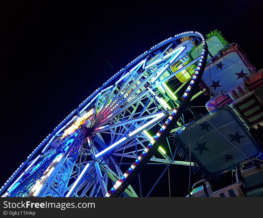 A colorful Ferris wheel seen from below at night.