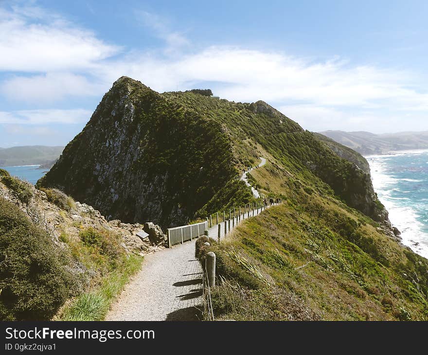 Empty path along hillside ridge overlooking coastline on sunny day. Empty path along hillside ridge overlooking coastline on sunny day.