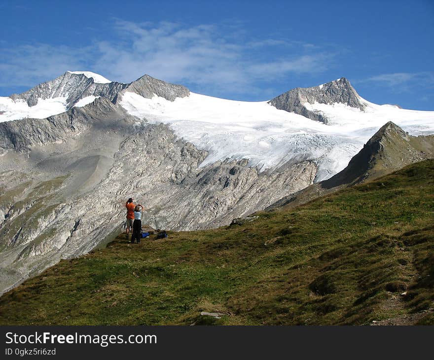 People on Green Grass Near Snow Mountain Under Blue Sky during Daytime