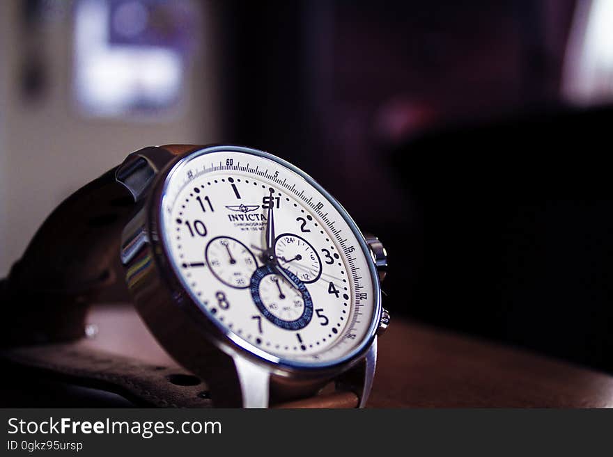 Close up of face on analogue wristwatch with leather strap.