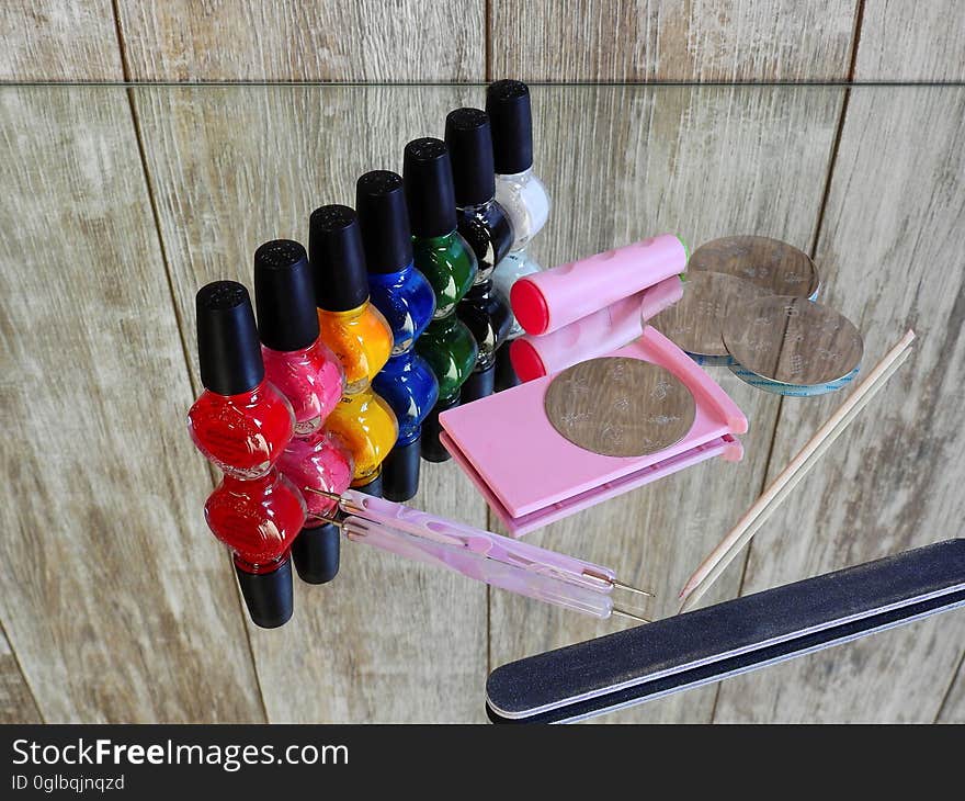 Colorful bottles of nail polish with manicure emery board on mirror. Colorful bottles of nail polish with manicure emery board on mirror.