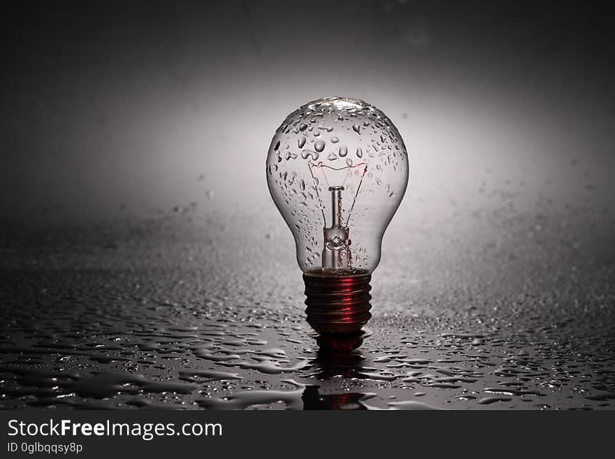 Close up of vintage incandescent light bulb in water with drops. Close up of vintage incandescent light bulb in water with drops.