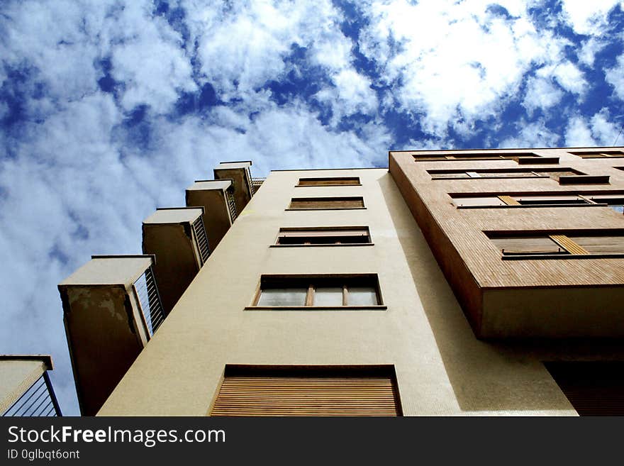 Facade of balconies and windows on apartment building against blue skies.