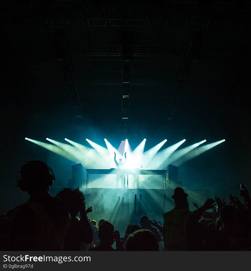 Performer in spotlights on stage during rave or concert in dark stadium. Performer in spotlights on stage during rave or concert in dark stadium.