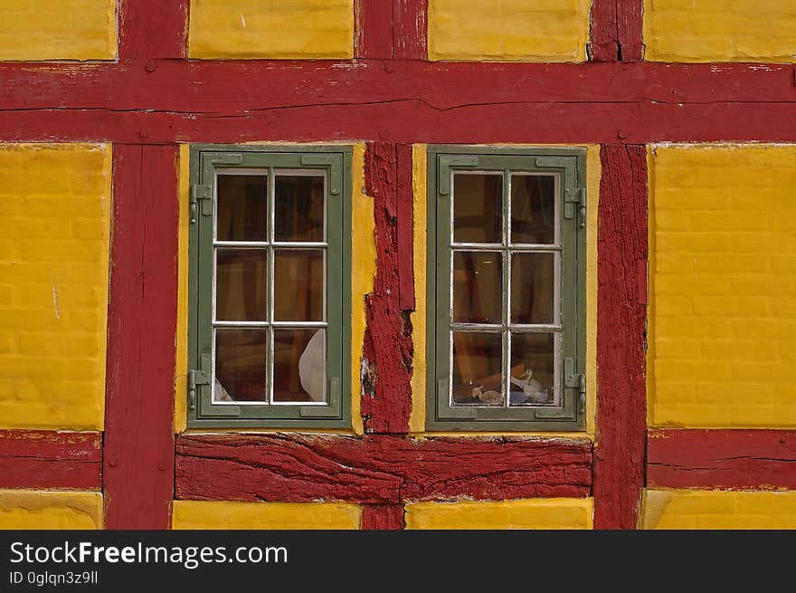 Windows with green frame in red and yellow painted brick building. Windows with green frame in red and yellow painted brick building.