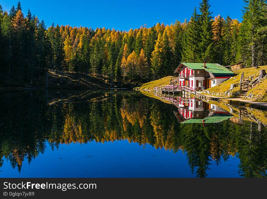 Lake house on banks of calm water reflecting with autumn foliage on sunny day. Lake house on banks of calm water reflecting with autumn foliage on sunny day.