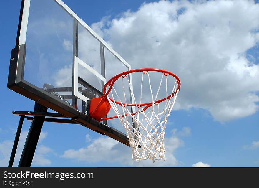 Basketball hoop on painted backboard against blue skies on sunny day. Basketball hoop on painted backboard against blue skies on sunny day.