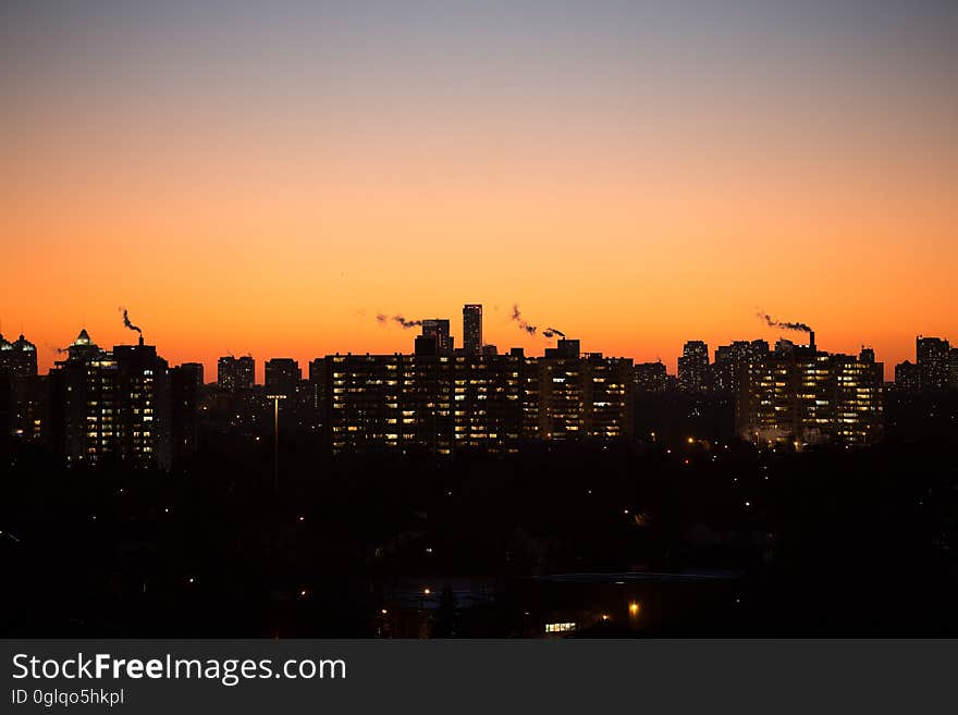 Silhouette of city skyline against orange skies at sunset. Silhouette of city skyline against orange skies at sunset.