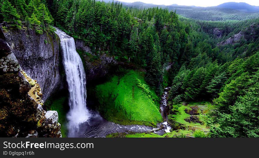 Waterfall over steep cliff in green pine forest. Waterfall over steep cliff in green pine forest.