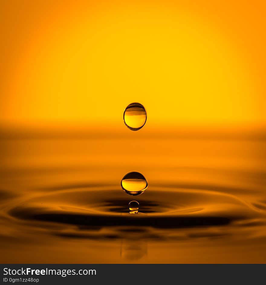 Drops of water falling in a pool in orange light. Drops of water falling in a pool in orange light.