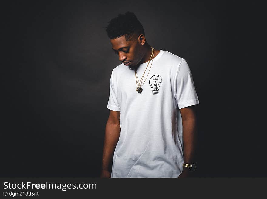 Studio portrait of young African American man wearing white t-shirt with light bulb and gold chains. Studio portrait of young African American man wearing white t-shirt with light bulb and gold chains.