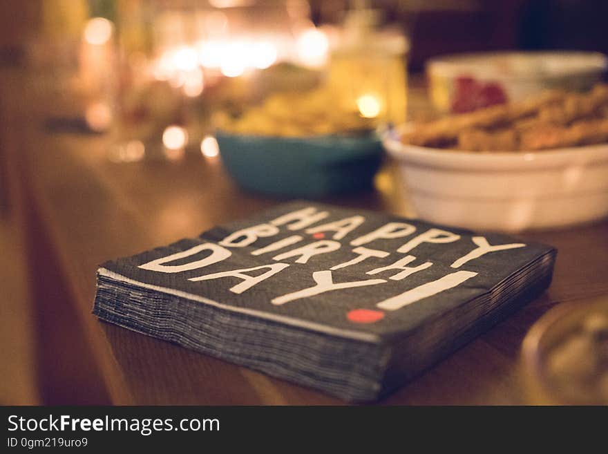 Close up of napkins with text graphics Happy Birthday on table with bowls of snacks. Close up of napkins with text graphics Happy Birthday on table with bowls of snacks.