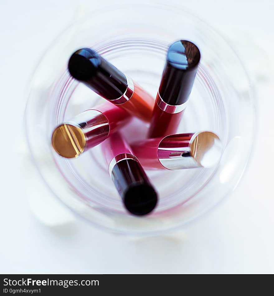 Overhead of colorful tubes of cosmetics in glass.