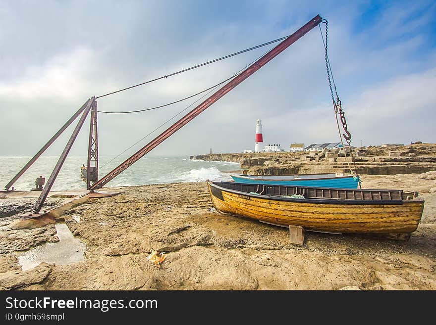 Fishing boats moored on rocky beach with lighthouse in background, Portland, Oregon, USA. Fishing boats moored on rocky beach with lighthouse in background, Portland, Oregon, USA.