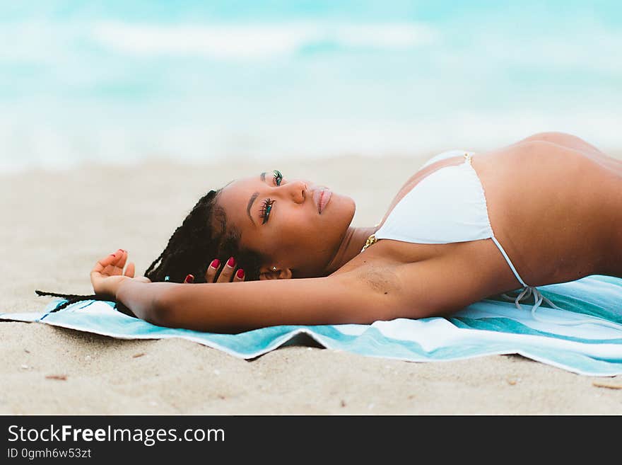 A woman flexing while lying on a sandy beach. A woman flexing while lying on a sandy beach.