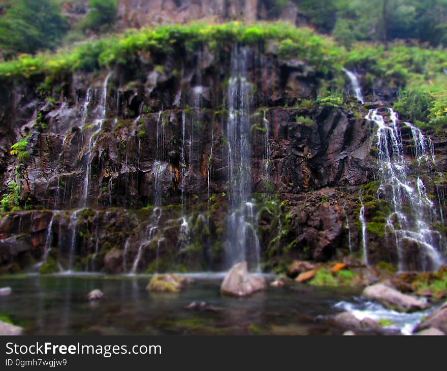 A rock wall with water falling down on it. A rock wall with water falling down on it.