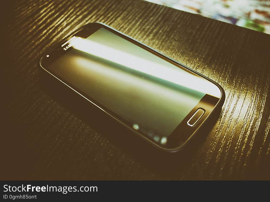 A close up of a modern smartphone on a wood surface.