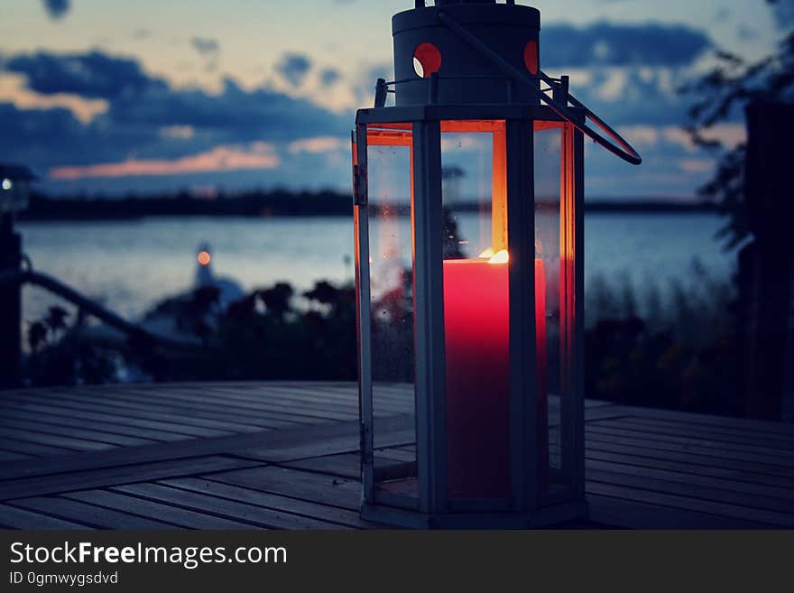 Candle lit lantern next to a beach.