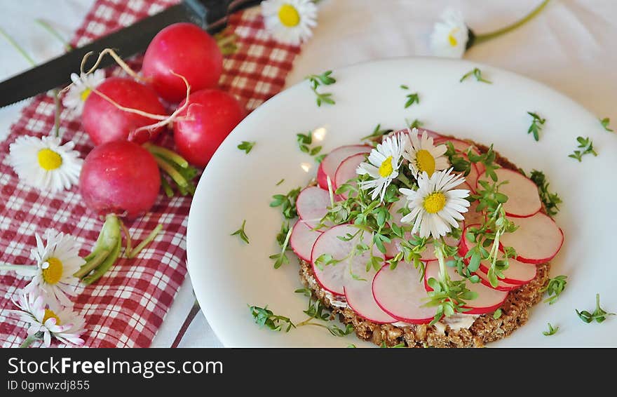 A plate of sliced radishes decorated with daisy flowers.