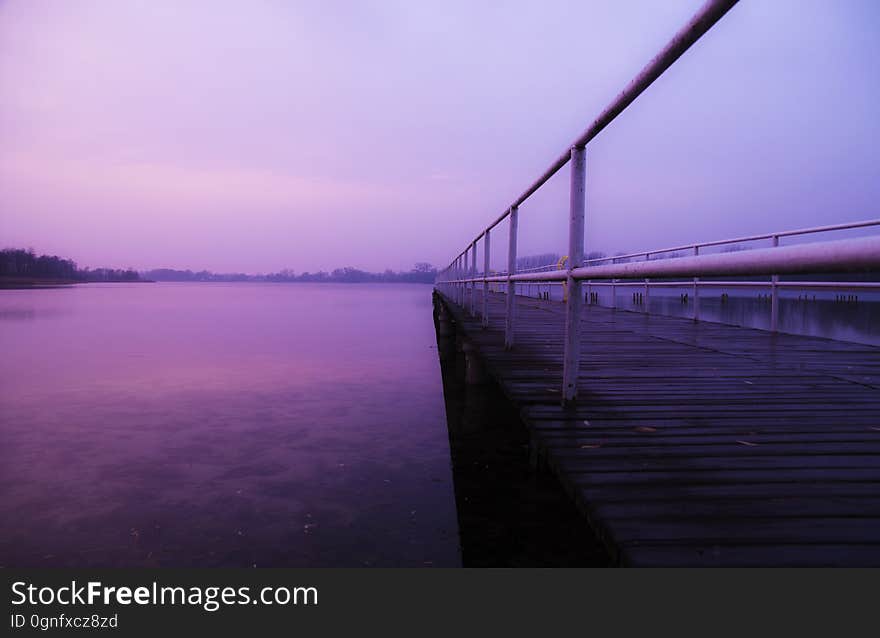 A jetty at dusk with blurred waters.