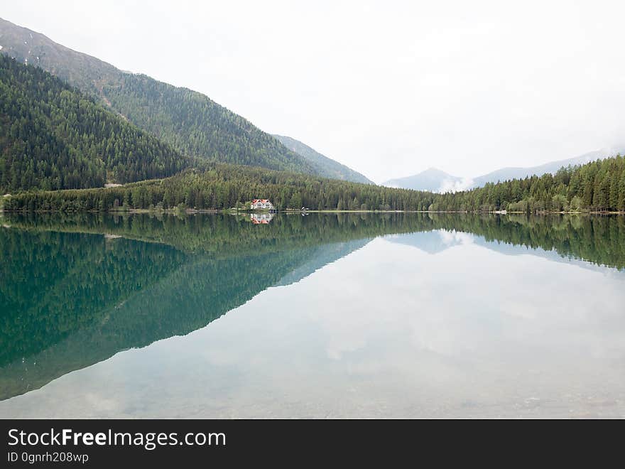 Lake in countryside with pine tree forest on hillside shores on sunny day. Lake in countryside with pine tree forest on hillside shores on sunny day.