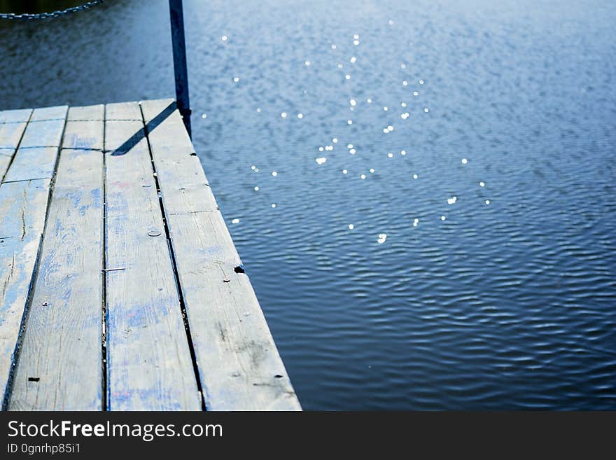 Rustic wooden dock over sunlit water. Rustic wooden dock over sunlit water.