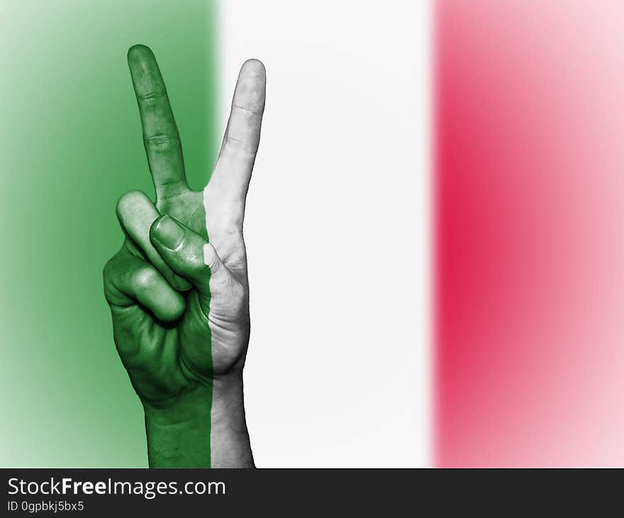 A hand showing the peace symbol and the Italian flag in the background. A hand showing the peace symbol and the Italian flag in the background.