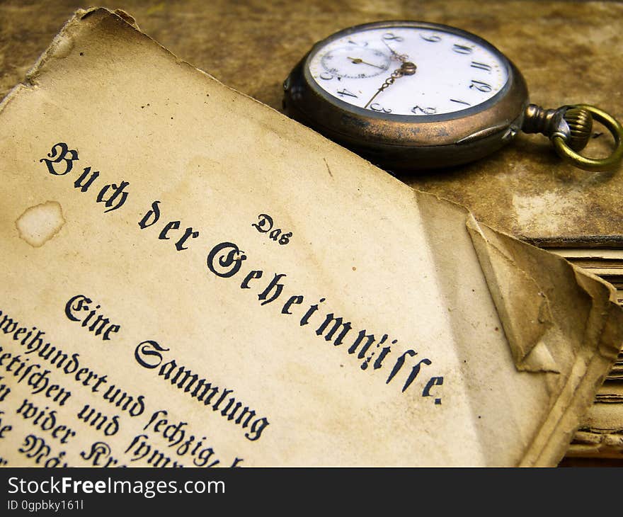 A close up of an old document and a watch. A close up of an old document and a watch.