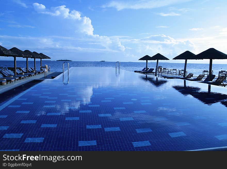 Poolside of infinity pool in resort along waterfront. Poolside of infinity pool in resort along waterfront.