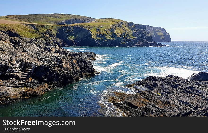 Rocky shores in cove along blue waterfront on sunny day. Rocky shores in cove along blue waterfront on sunny day.