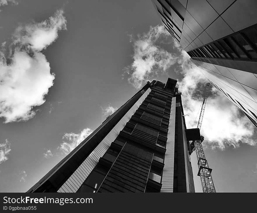 High rise building under construction with crane against cloudy skies in black and white. High rise building under construction with crane against cloudy skies in black and white.