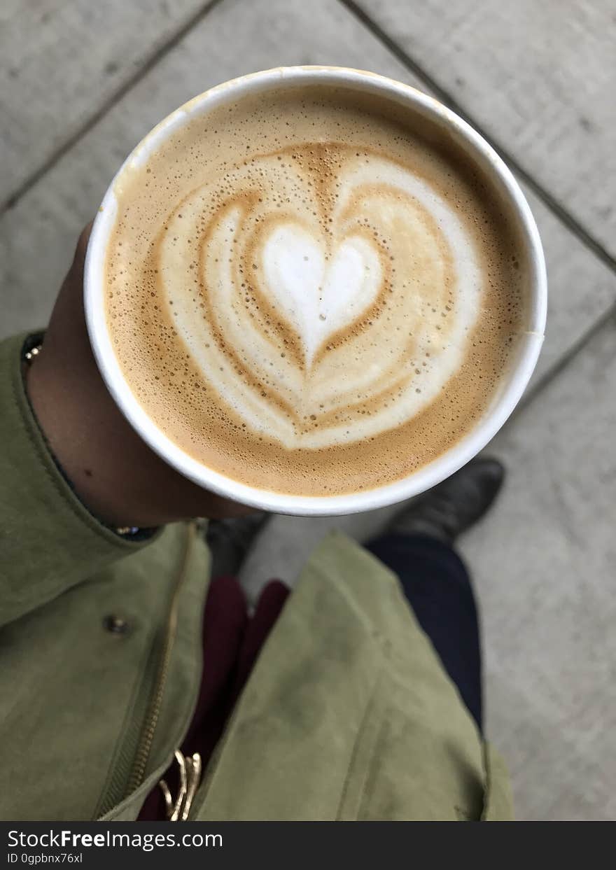 A close up of a coffee cup with heart shaped foam.